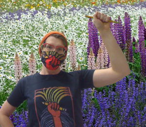 "Teacher Fist" union-made t-shirt (design by RLM Arts) worn by a happy union worker in front of a field of lupine
